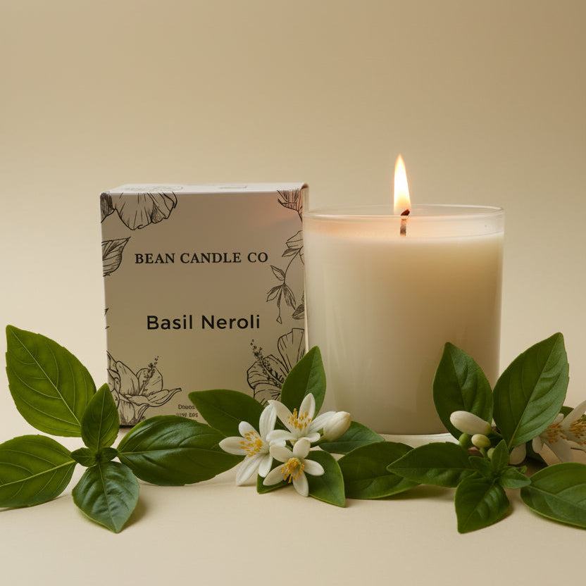 Candle with 'Bean Candle Co' packaging and basil leaves on a beige background