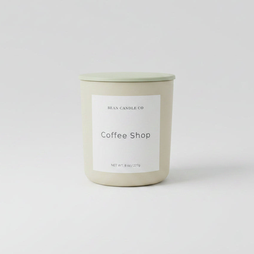 Candle labeled 'Coffee Shop' on a reflective surface 