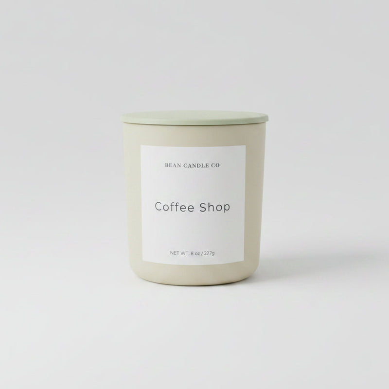Candle labeled 'Coffee Shop' on a reflective surface 
